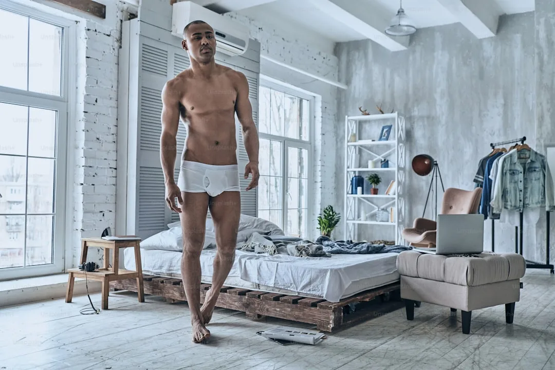 Pleine longueur d&rsquo;un beau jeune homme africain regardant ailleurs tout en marchant dans la chambre à coucher à la maison